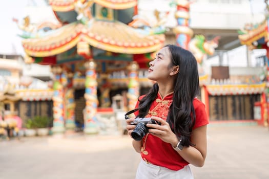 A young woman photographs the vibrant shrine during Chinese New Year celebrations capturing cultural worship and joy.