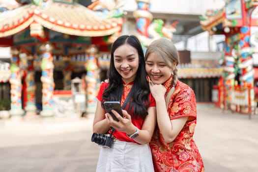 Two friends joyfully celebrate Chinese New Year at a colorful shrine capturing the essence of worship and festive spirit.
