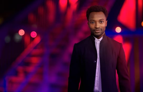 man at night outside wearing black suit urban lifestyle businessman red and blue lights city nightclubs