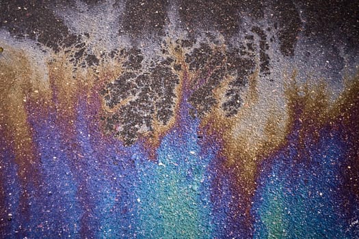 Gasoline or oil slick creating a rainbow chemical reaction on a wet asphalt road surface.