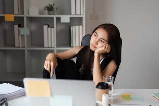 A stressed office worker sits at a desk with a laptop and coffee, reflecting the pressures of a modern work environment.