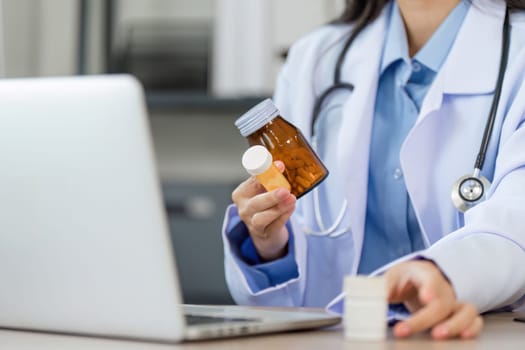 A doctor in a white coat holds a medicine bottle while conducting an online consultation, showcasing modern telemedicine practices.