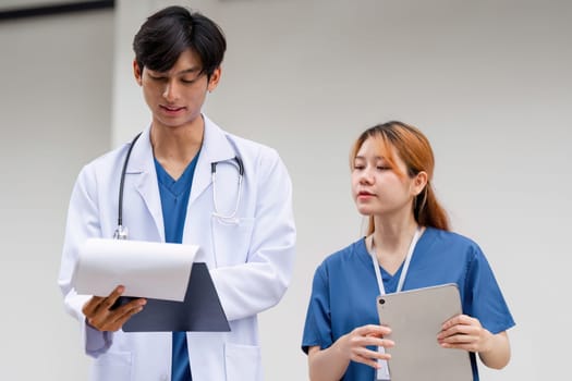 A male doctor and his assistant discuss patient care, showcasing teamwork and professionalism in a medical setting.