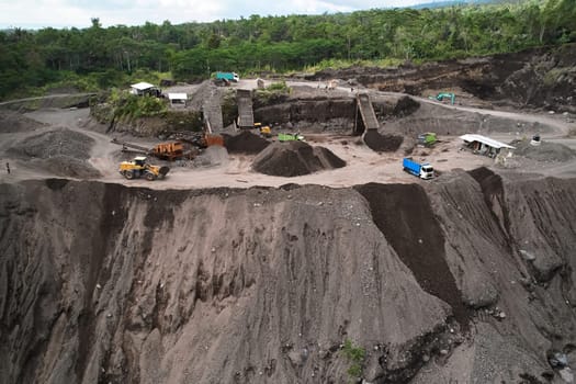 A stone quarry in Indonesia. Large equipment such as bulldozers and dump trucks are working on the site