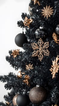 A beautifully decorated black Christmas tree with gold ornaments.
