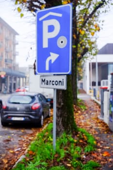 Cremona, Italy - November 7th 2024 Blue parking sign with white p and right turn arrow, indicating covered parking access on marconi street