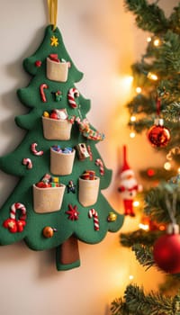 Felt advent calendar shaped like a christmas tree features numbered pockets for candies and toys. brightly lit setup with festive decor including stockings, baubles, and a small tree, creating an inviting holiday atmosphere.