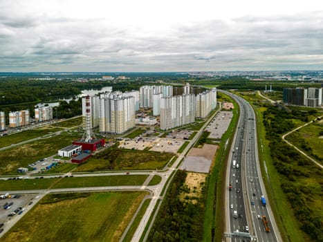 An aerial shot beautifully captures urban apartments, expansive highways, and lush greenery surrounding them