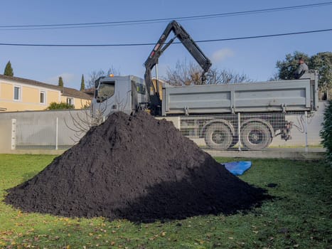 France, Gironde, December 2024, Delivery of topsoil by truck crane to the garden of a residential house. High quality photo