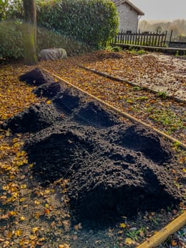 Adding heaps of topsoil to the vegetable patch in the garden of a residential house. High quality photo