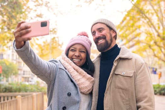 Happy friends taking photos on smartphone having fun outdoors. Spouses enjoy the weekend in a trendy shopping mall.