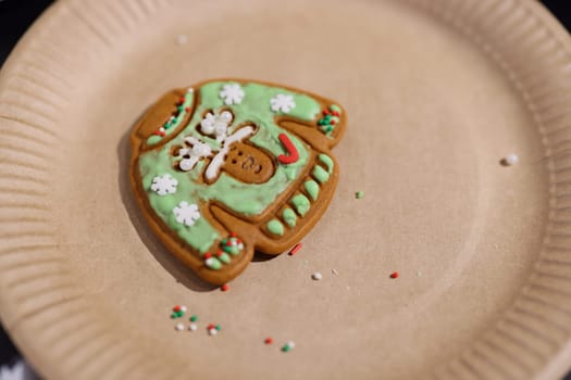 A charming gingerbread cookie shaped like a sweater, decorated for the holidays with icing and festive sprinkles.