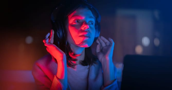 A young girl holds headphones and is listening and composing music, a woman sits with a laptop by the window in her room, works and enjoys the sound.