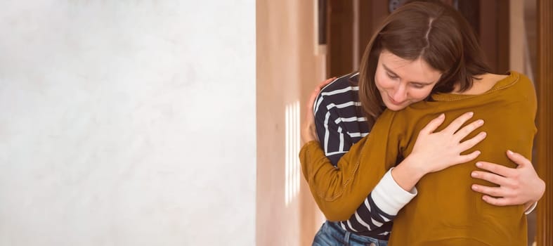 Two friends are embracing in the sun and happy to meet each other. Girls celebrate the holidays or anniversary and hug tightly and warm, feel an emotional connection and love, smiley face closeup.