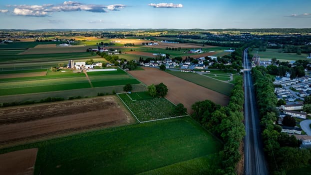 Vast fields stretch across the Pennsylvania countryside, showcasing a mix of agricultural land, patches of green, and distant hills, all bathed in the warm glow of the setting sun.