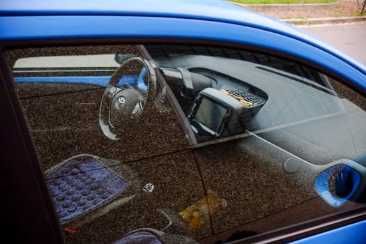 Cremona, Italy - November 7th 2024 Interior view of a car through a window, showing steering wheel, dashboard, and beaded seat cover