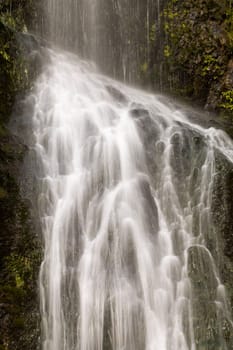 Beautiful water falling over rocks and moss, captured with a long exposure time. Piha, New Zealand