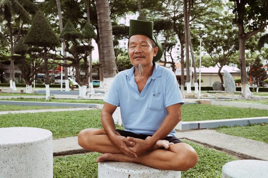 An elderly man is engaged in relaxing exercises, yoga outdoors. The concept of wellness, motivation to take care of health.Nha Trang, Vietnam - July 21, 2024