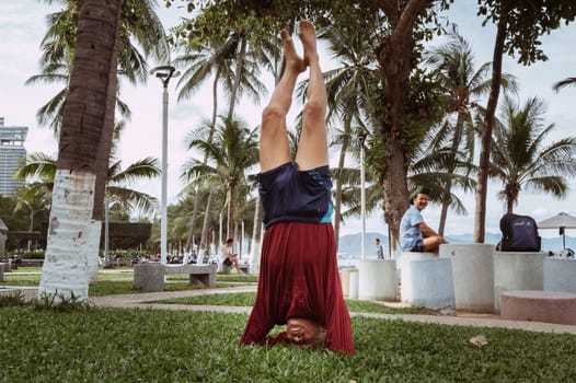 An elderly man is engaged in relaxing exercises, yoga outdoors. The concept of wellness, motivation to take care of health. Nha Trang, Vietnam - July 21, 2024