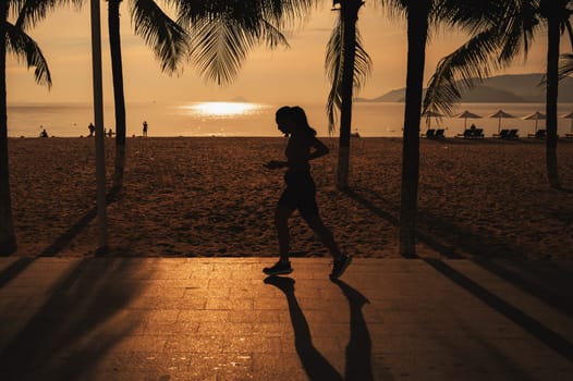 The silhouette of a Woman running alone at beautiful sunset in the beach. Summer sport and freedom concept.