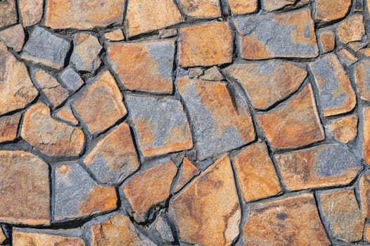 Fragment of a wall from a chipped stone. Wide panoramic stone pattern. The surface of natural masonry. The structure is in the grunge style.