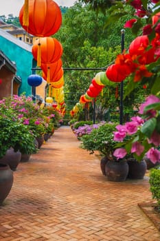Red paper lanterns hung in the courtyard of a house on a sunny day among the lush greenery in an eastern country. traditional Chinese New Year decoration