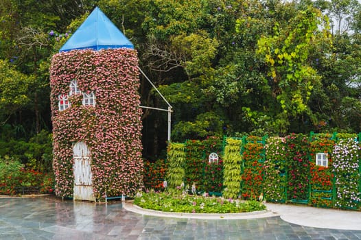 A picturesque view of the tower covered with live flowering plants located in the park or in the backyard of the house
