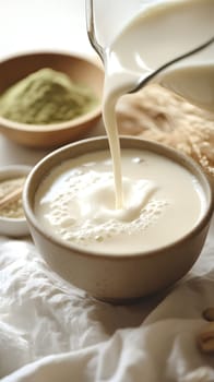A bowl of fresh milk being poured, surrounded by ingredients.