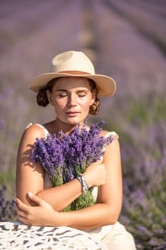 A woman is sitting in a field of lavender flowers and wearing a straw hat. She is smiling and holding a bouquet of flowers. Scene is peaceful and serene, as the woman is surrounded by the beauty of nature.