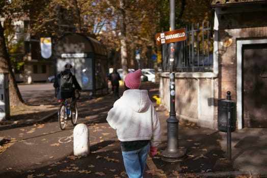 A person casually walks through a vibrant autumn street that is beautifully adorned with falling leaves all around