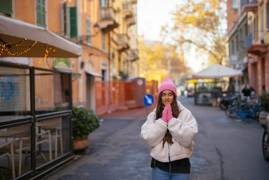 A cheerful young woman in cozy winter attire beams joyfully on a quaint city street, capturing a blissful moment