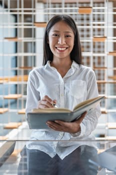 A joyful young woman reads a book in a stylish indoor setting. Her casual look and warm smile reflect a passion for learning and a love for reading.