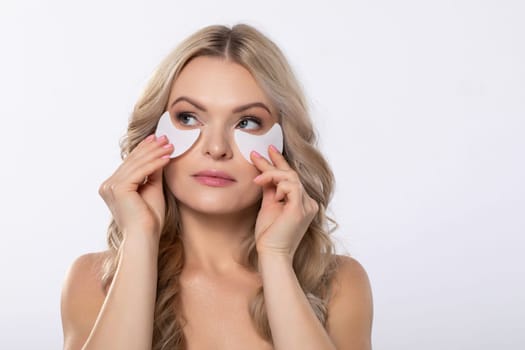 A woman applies eye masks designed for hydration and skincare while enjoying a bright and cheerful setting