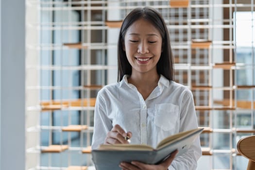 A young woman engages with a book in a bright, stylish indoor setting, reflecting concentration and joy while showcasing a passion for learning and creativity.