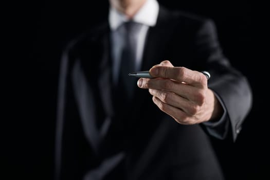 A hand holding a marker turned to the camera against a dark background