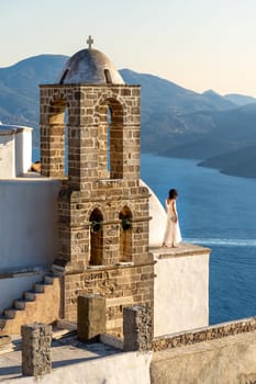 Woman in white dress looking at the sea in church Panagia Thalassitra, Plaka, Milos