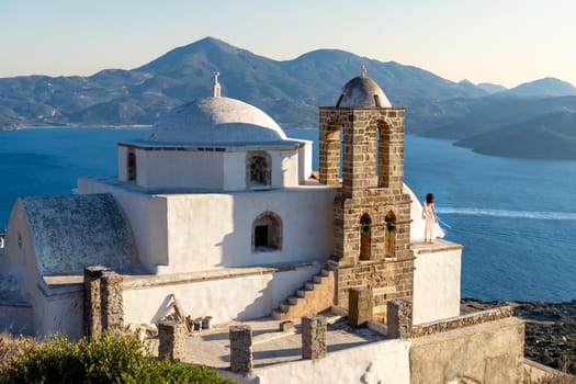 Woman in white dress looking at the sea in church Panagia Thalassitra, Plaka, Milos