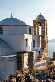 Woman in white dress looking watching her husband at the sea in church Panagia Thalassitra, Plaka, Milos