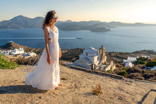 Woman in white dress in Plaka, Milos, at sunset