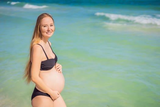 Radiant pregnant woman in a swimsuit, amid the stunning backdrop of a turquoise sea. Serene beauty of maternity by the shore.