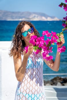 Young woman in white dress playing with a bougainvillea