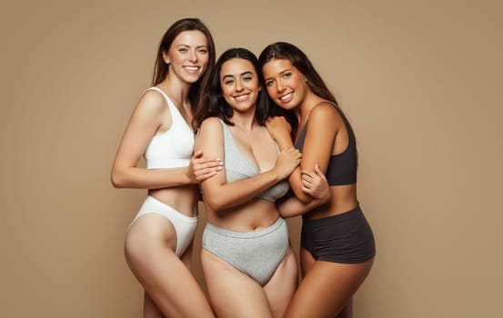 Glad millennial pretty diverse women in underwear with different body types hugs, enjoy beauty care, isolated on beige background, studio. Motivation for self love, wellness, ad and offer