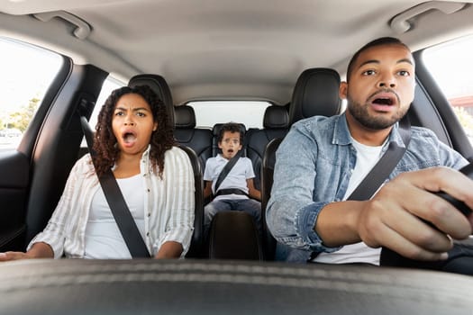 Car accident. Shocked African American family father, mother and son driving automobile having problem and risk of auto crash riding in city. Transportation and traffic issues on road concept