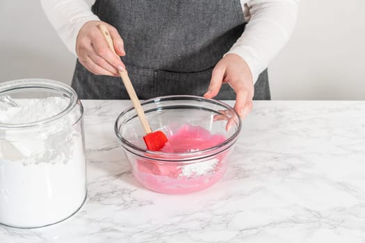 Mixing ingredients in a large glass mixing bowl to make homemade royal icing.