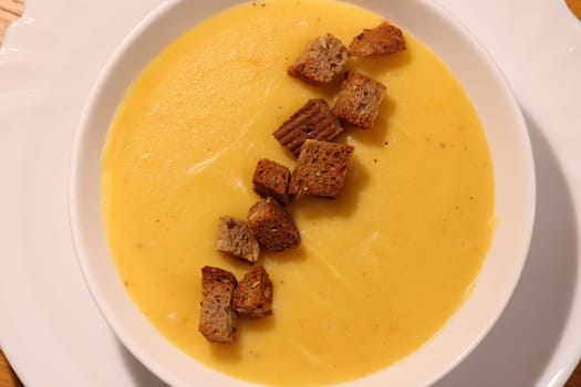 A vibrant bowl of creamy pumpkin soup topped with crunchy croutons, perfect for seasonal comfort and warmth