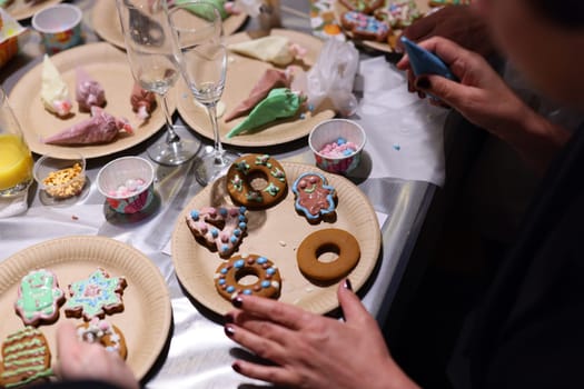 People are joyfully decorating delicious cookies with vibrant icing and toppings at a fun festive event