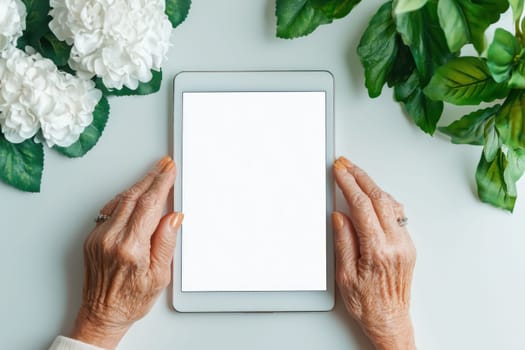 An Elderly hands holding tablet surrounded by flowers and greenery, conveying sense of connection and technology