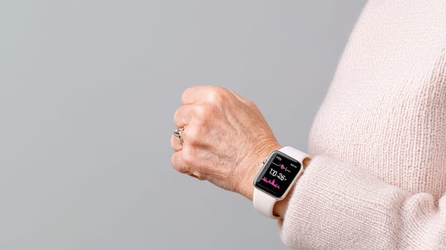 A Senior hands holding smart watch displaying health metrics, showcasing technology and wellness
