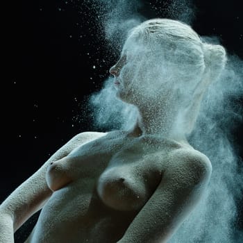 Nude girl in white dust cloud profile shot against black background