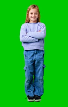 Child wearing a blue sweater and light blue pants stands confidently in front of a green background in a studio